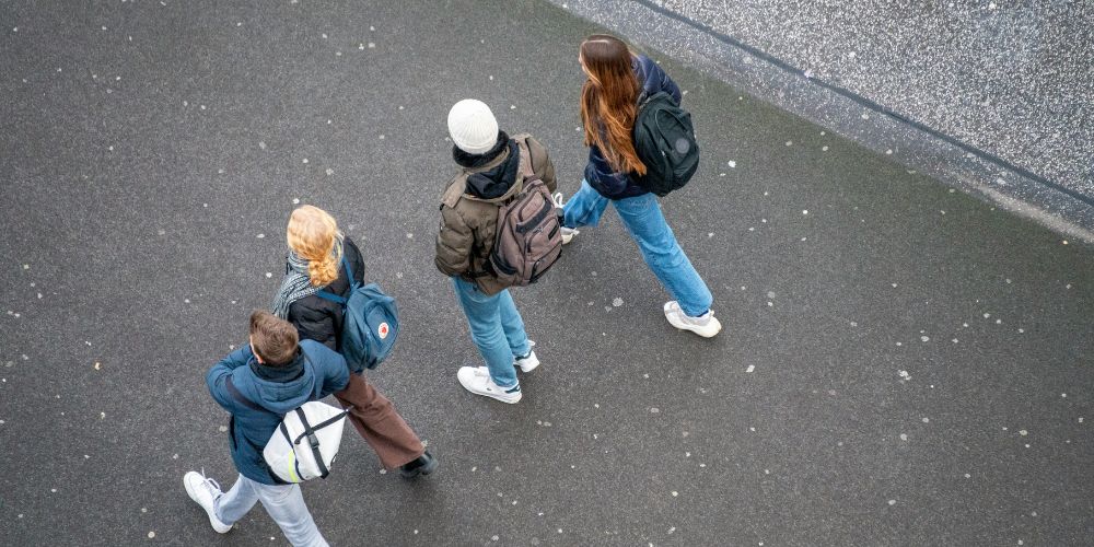 "Group of young people walking together with backpacks, representing young carers balancing school life and caring responsibilities – used for an Action for Family Carers case study story."
