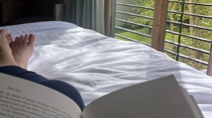 Carer laying on a bed reading a book relaxing
